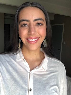 Woman smiling with seashell earrings in wrinkled white shirt