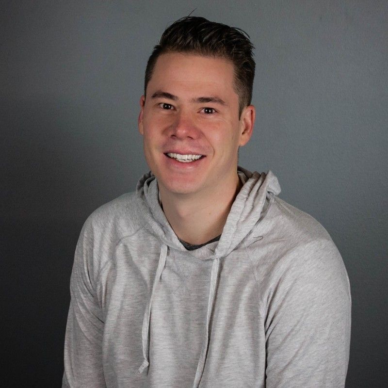 Photo of Brian in front of a grey background.