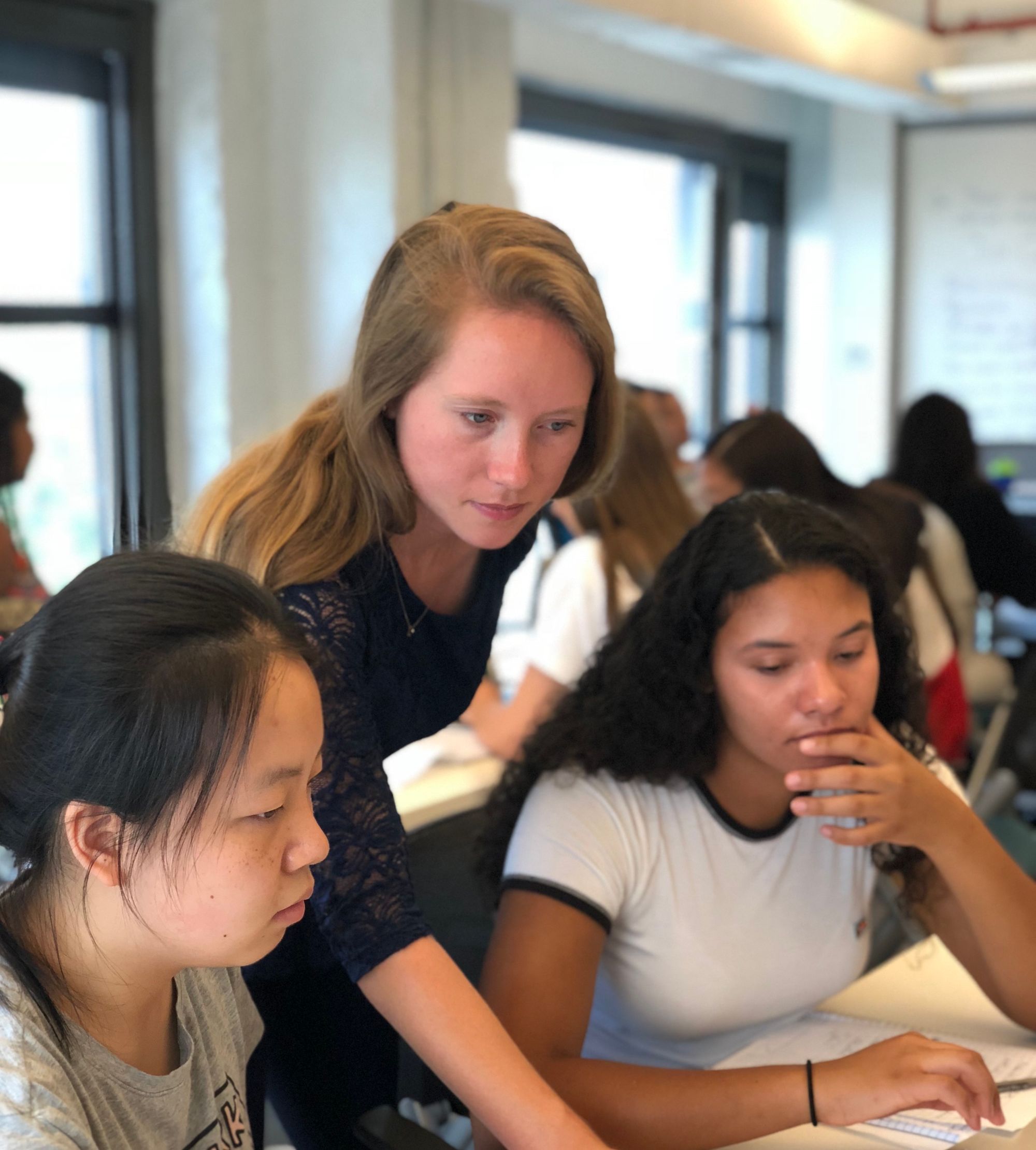 Woman teaching two girls in classroom.