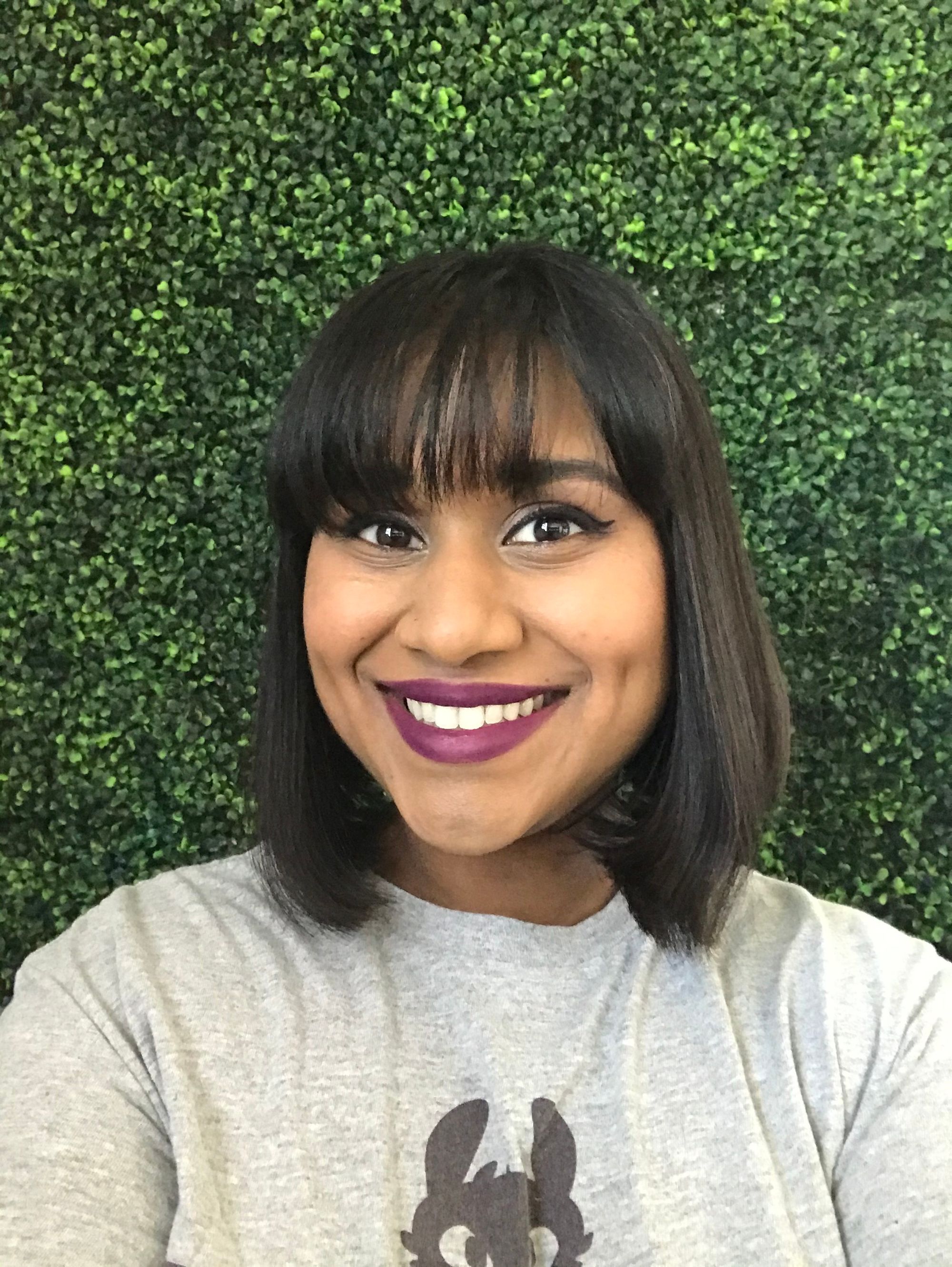 Woman smiling at camera in front of a green backdrop